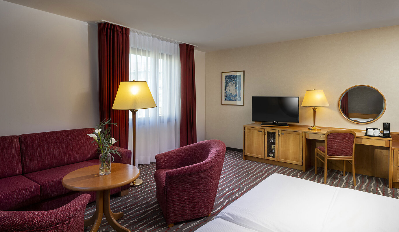 Comfortable studio room at the Maritim Hotel Magdeburg with seating area, desk, and modern TV.
