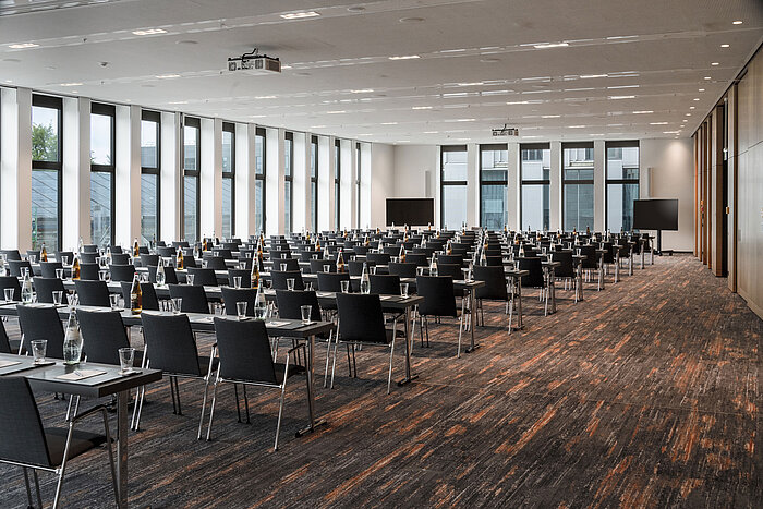 Grande salle de conférence à l'hôtel Maritim Ingolstadt avec sièges en rangée, grandes fenêtres et technologie de pointe.