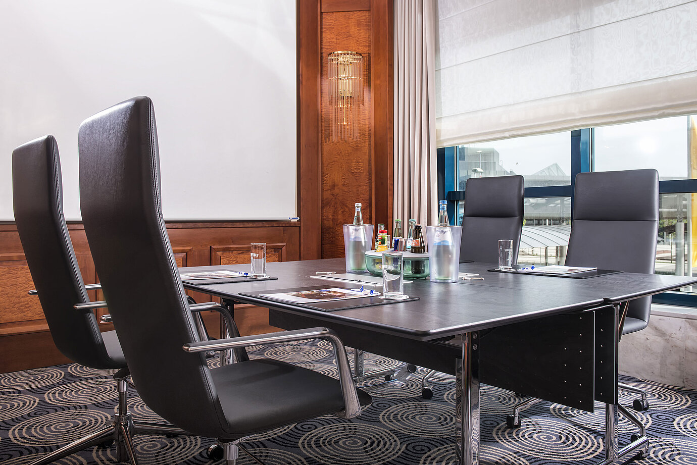 Sala de reuniones moderna con mesa grande, sillas de cuero y luz natural.