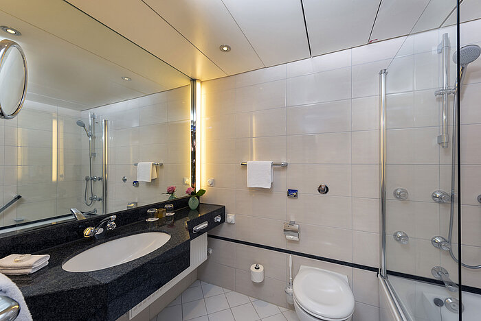 Salle de bain moderne du Maritim Hotel Frankfurt avec grand miroir, lavabo élégant et baignoire-douche.