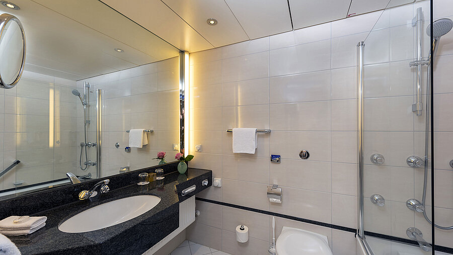 Bagno moderno del Maritim Hotel Frankfurt con grande specchio, lavabo elegante e vasca-doccia.