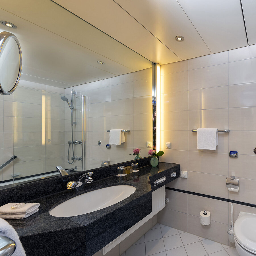 Bagno moderno del Maritim Hotel Frankfurt con grande specchio, lavabo elegante e vasca-doccia.