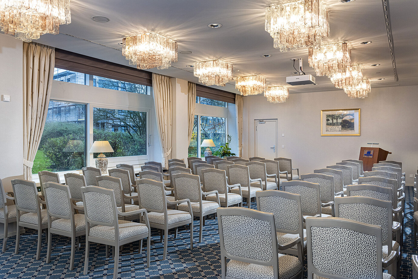 Salon Helsinki nel Maritim Hotel Kiel, sala conferenze con file di sedie, lampadari e grandi finestre con vista sul verde.