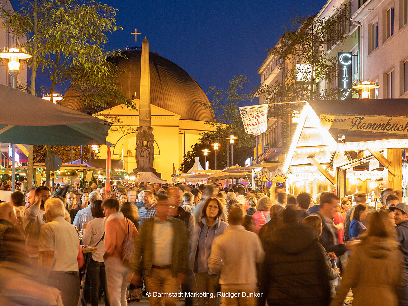 Busy city festival with market stalls and church at night