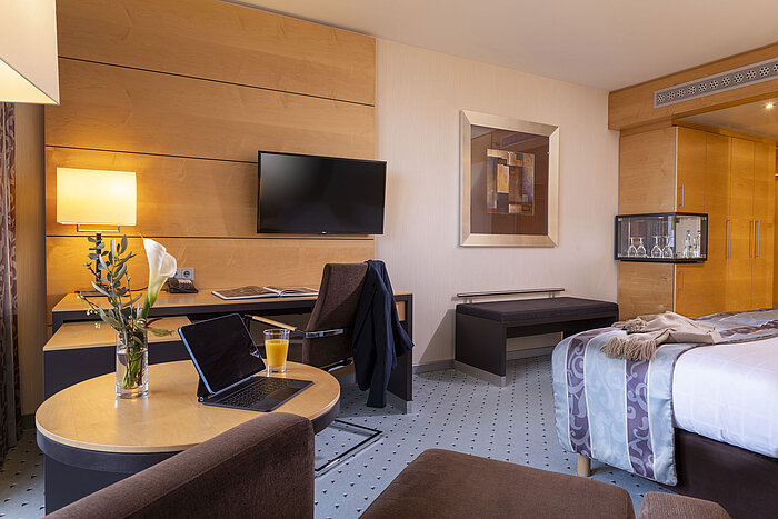 Habitación comfort en el Maritim Hotel Düsseldorf con escritorio, televisor de pantalla plana, sillón cómodo y decoración elegante.