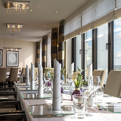 Elegante decoración de mesa en la sala VIP del Maritim Hotel Düsseldorf con grandes ventanas y ambiente sofisticado.
