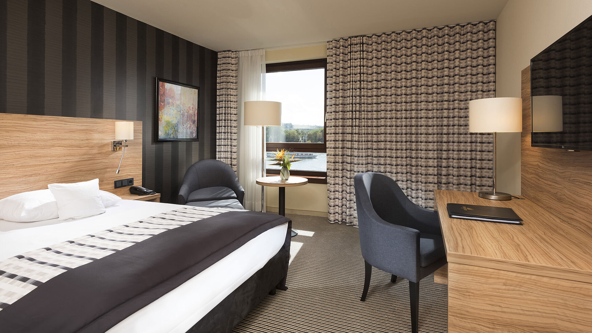 Habitación doble moderna en el Maritim Hotel Königswinter con vistas al Rin y mobiliario elegante.