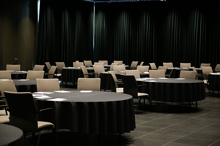 Sala con mesas redondas, manteles negros y sillas en el Maritim Hotel Plaza Tirana