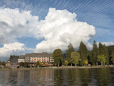 Vue extérieure de l’hôtel Maritim Titisee avec arbres et lac sous un ciel bleu