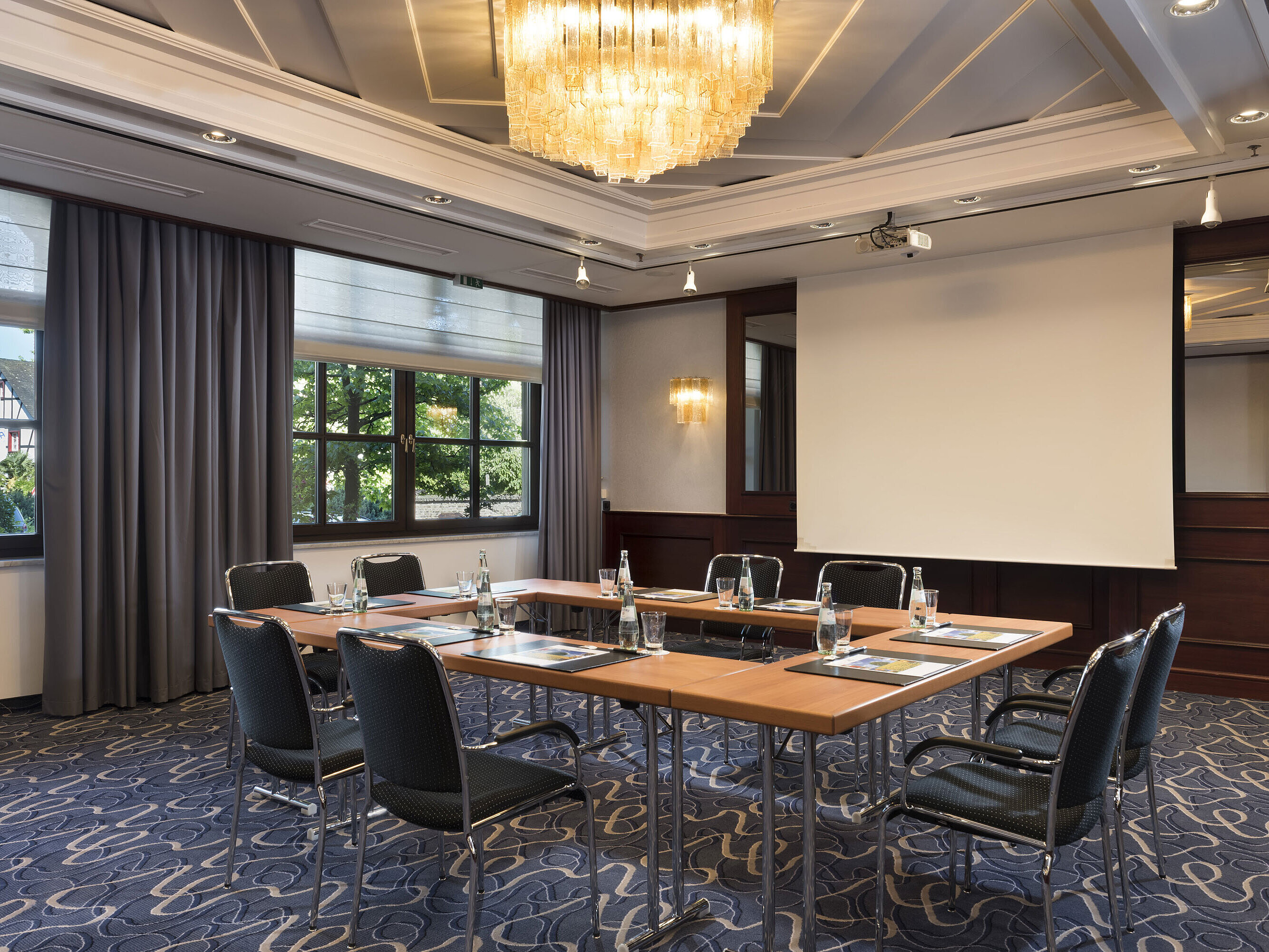 Salle de réunion lumineuse avec technologie moderne, grandes fenêtres et lustre élégant au Maritim Hotel Königswinter.