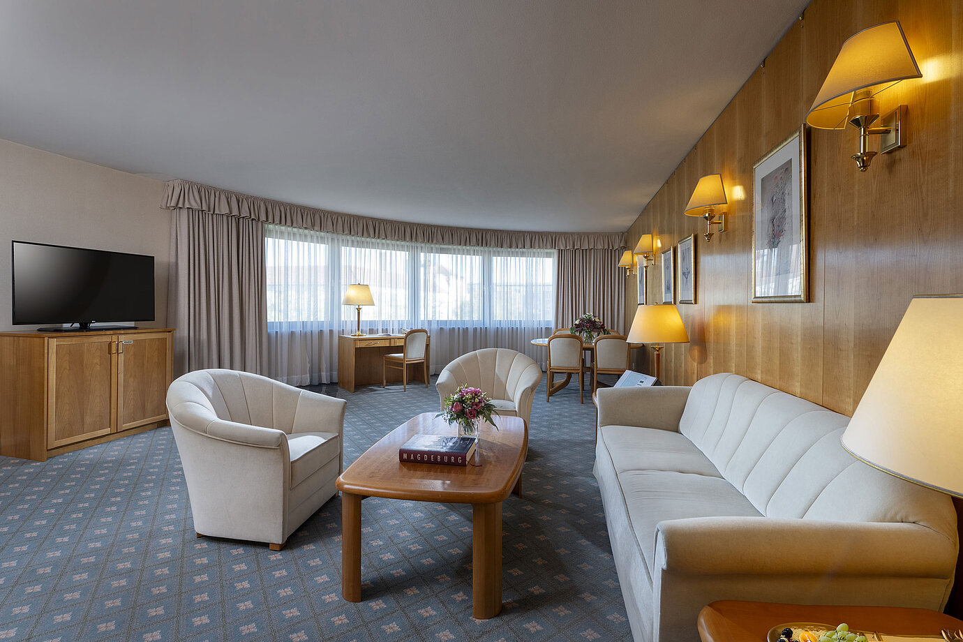 Spacious living room of a suite at the Maritim Hotel Magdeburg with elegant furnishings, seating area, and workspace.