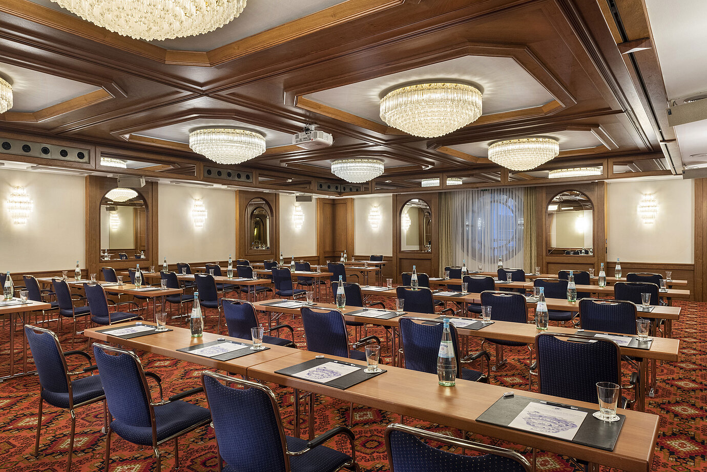 El salón Colonia con elegantes candelabros y filas de asientos en un ambiente clásico de sala de conferencias.