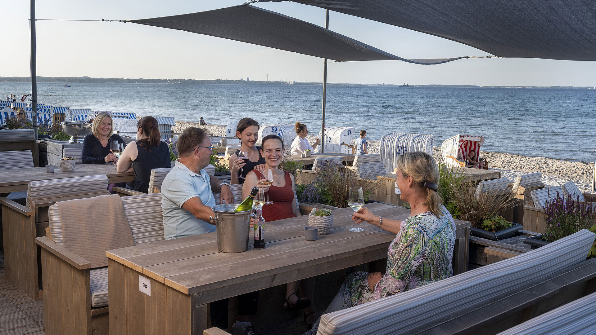 Beach Lounge Group of guests at the beach bar of Maritim Seehotel Timmendorfer Strand enjoying drinks with sea view and beach chairs.