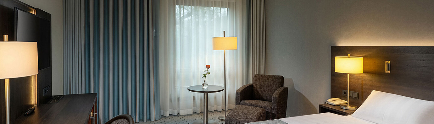 Classic Queen room with queen-size bed, seating area, desk, warm lighting and classic interior design.