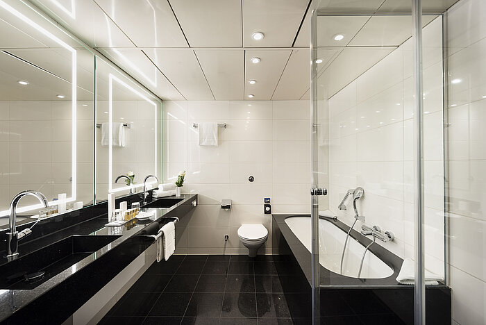 Elegante baño con lavabo doble, bañera y accesorios modernos en el Hotel Maritim Bonn, elegante y funcional.