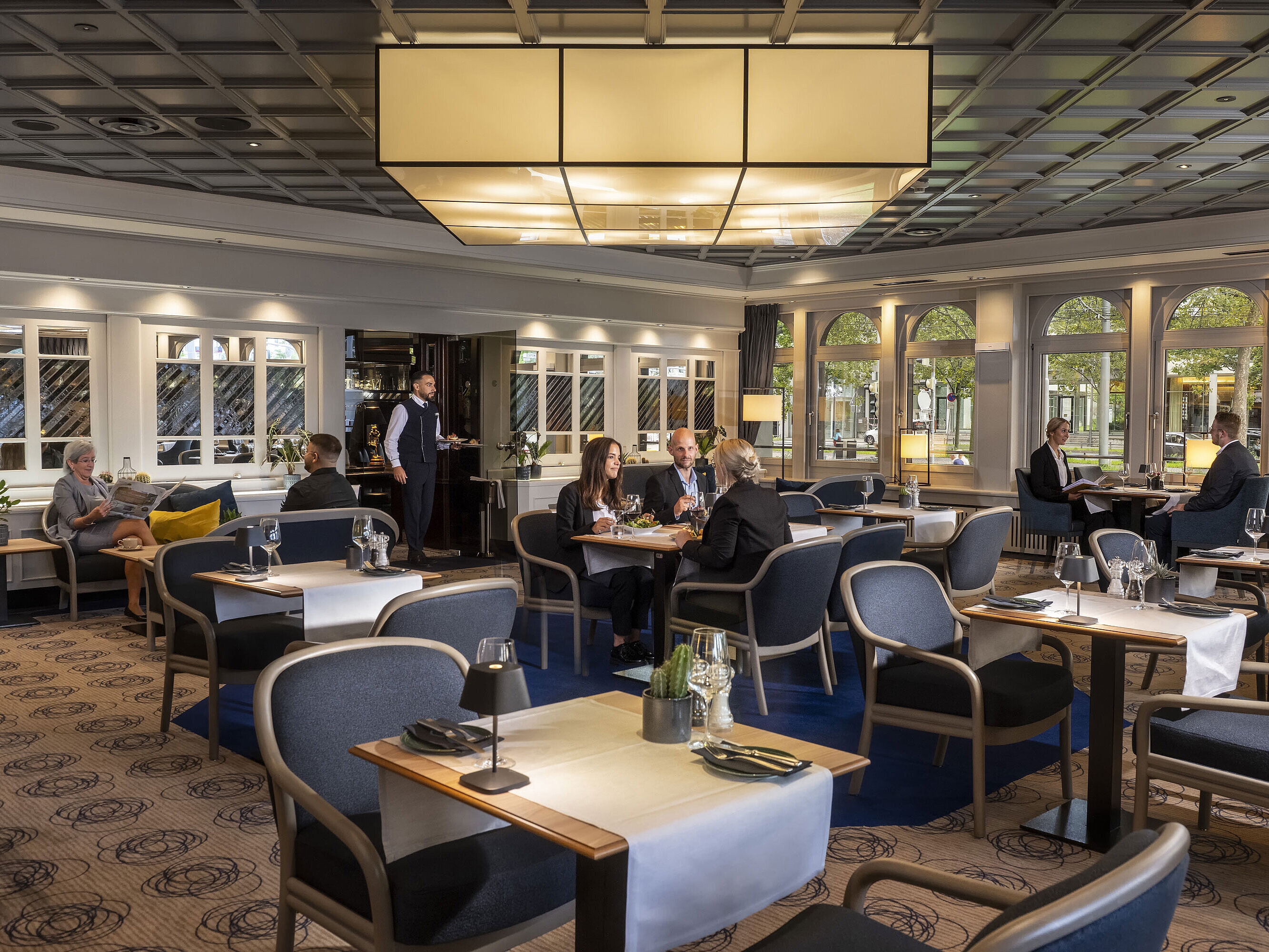  Restaurante elegante donde los huéspedes cenan y se relajan. Mobiliario moderno y grandes ventanales con vistas.