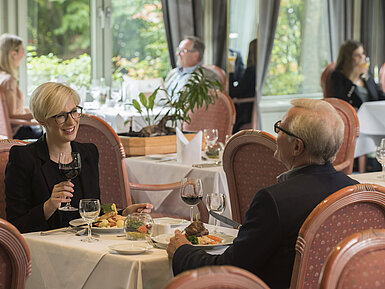 Guests dining at the stylish restaurant of Maritim Hotel Bad Salzuflen with garden view