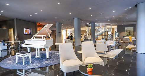 Elegante vestíbulo con piano blanco y zonas de estar en el Maritim Hotel Plaza Tirana