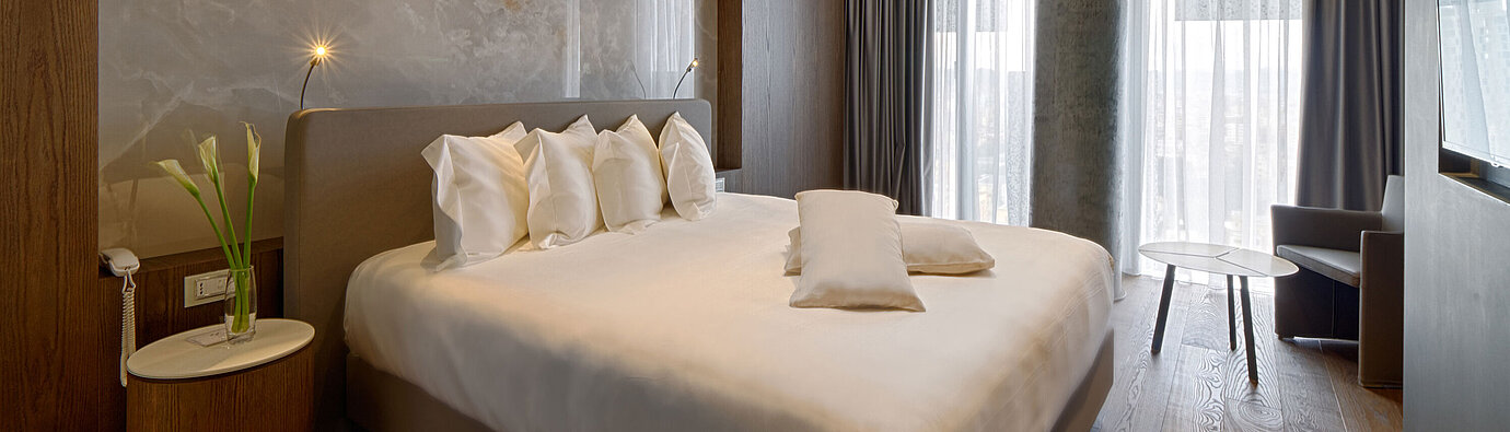 Habitación tranquila con cama grande, pared de piedra y cortinas suaves en el Maritim Hotel Plaza Tirana