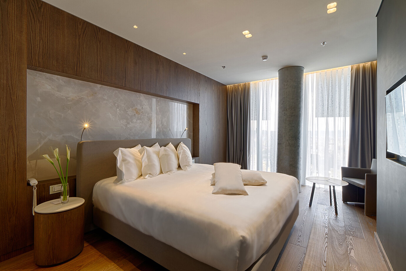 Quiet room with large bed, natural stone wall and soft curtains at Maritim Hotel Plaza Tirana