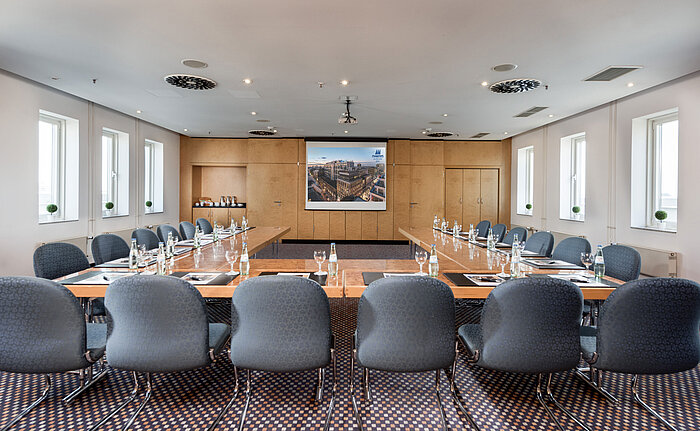 Salle de réunion avec disposition rectangulaire des tables et technologie de présentation moderne à l’hôtel Maritim Berlin.