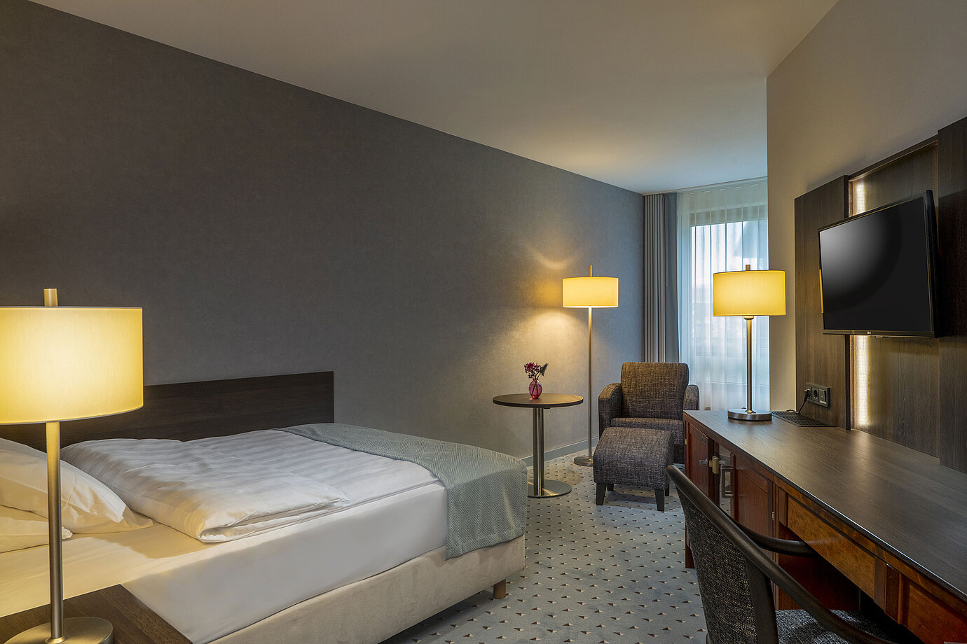 Modernly furnished Classic room with desk, TV, seating area, and comfortable bed at Maritim Hotel Bremen.