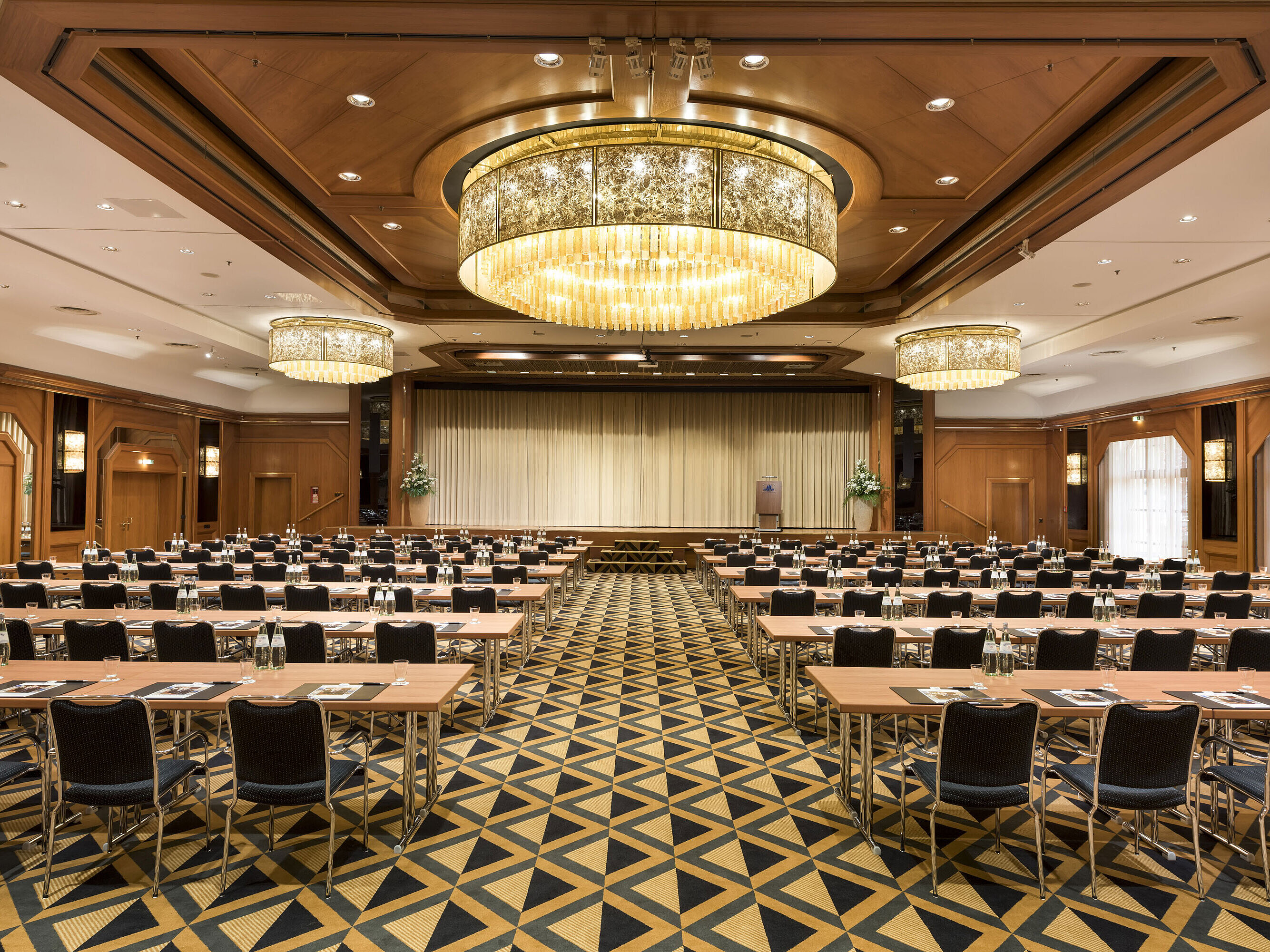 Salle de conférence élégante avec scène, lustres et sièges modernes au Maritim Hotel Königswinter.