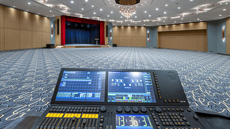 Sala Barbarossa moderna en el Maritim Hotel Würzburg, con escenario y controles de iluminación para eventos y conferencias.
