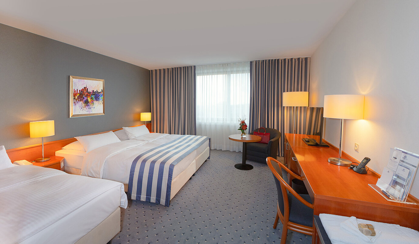 Chambre Classic familiale au Maritim Hotel Ulm avec coin salon confortable et tons chauds.