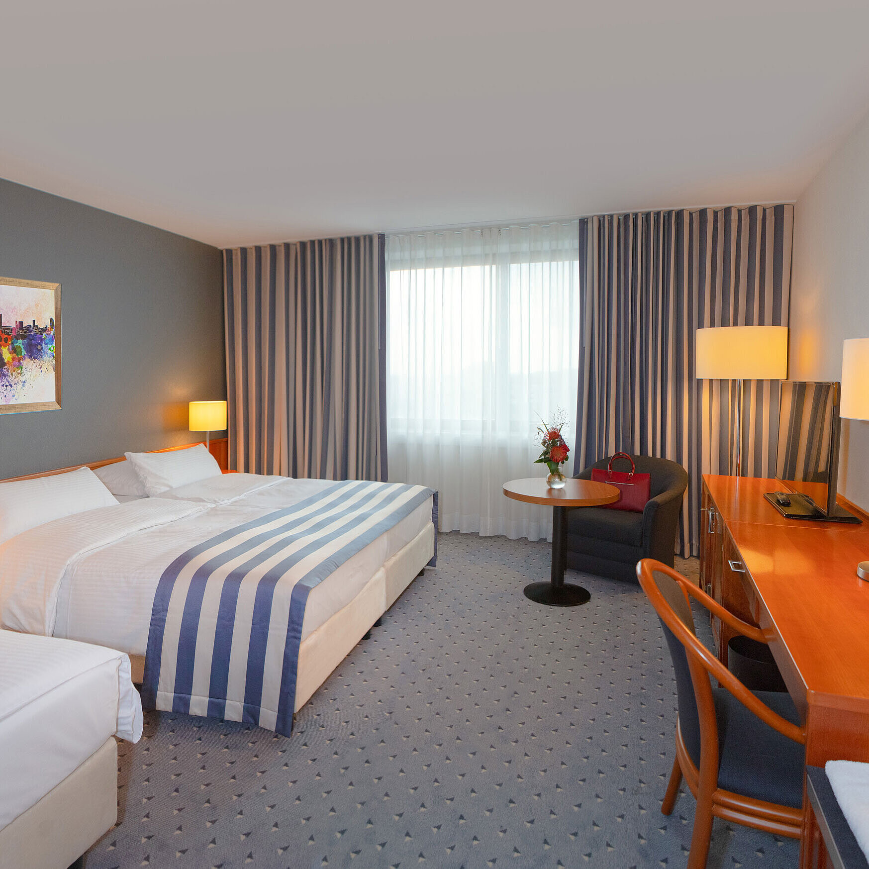 Chambre Classic familiale au Maritim Hotel Ulm avec coin salon confortable et tons chauds.