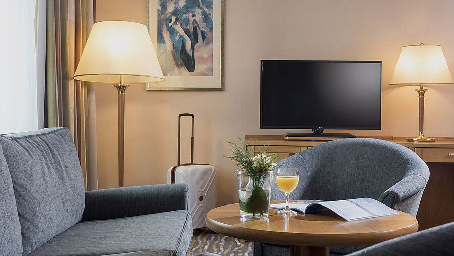 Camera d'hotel confortevole con scrivania, TV a schermo piatto, area salotto con luce naturale e interni eleganti.