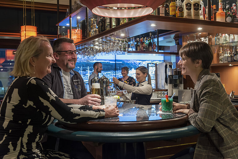 Clientes conversando y disfrutando de bebidas en el bar del Maritim Hotel Travemünde