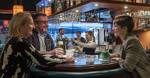 Clientes conversando y disfrutando de bebidas en el bar del Maritim Hotel Travemünde
