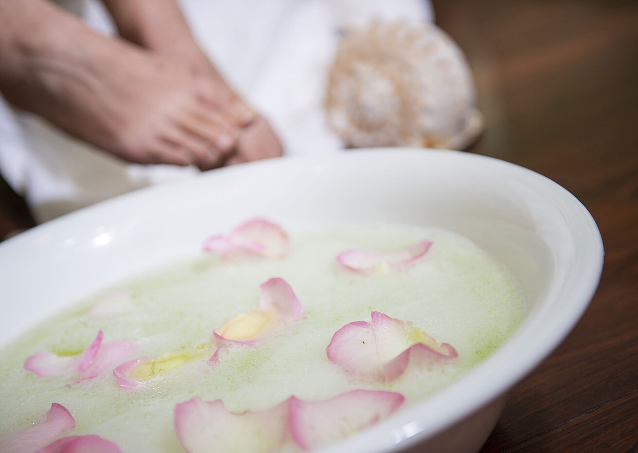 Pediluvio con petali di rosa in una ciotola durante un trattamento spa all'Hotel Maritim per rilassamento e cura.