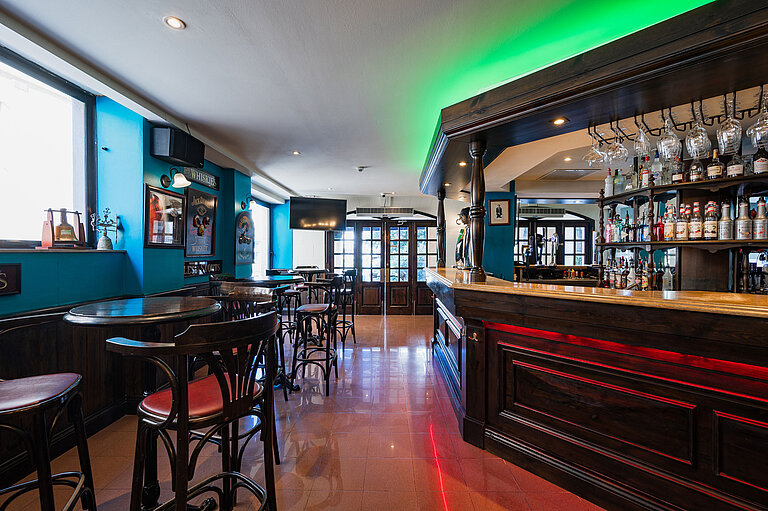 Elegante pub-bar del Maritim Antonine Hotel & Spa Malta con interni in legno scuro, selezione di liquori e accoglienti aree salotto.