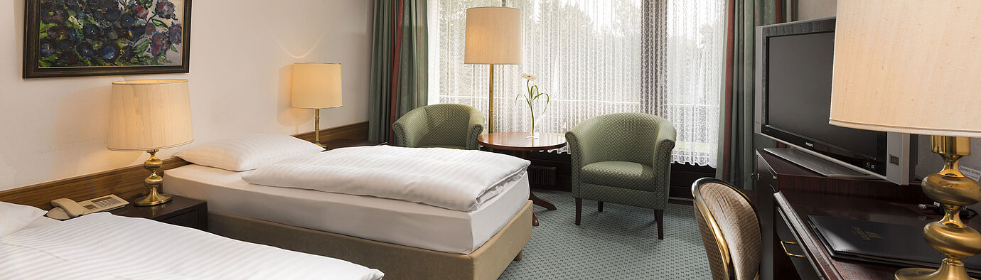 Dos camas, sillones y balcón en el Maritim Hotel Bad Salzuflen