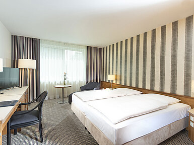 Modern hotel room with striped wall, double bed and desk at Maritim Hotel Stuttgart