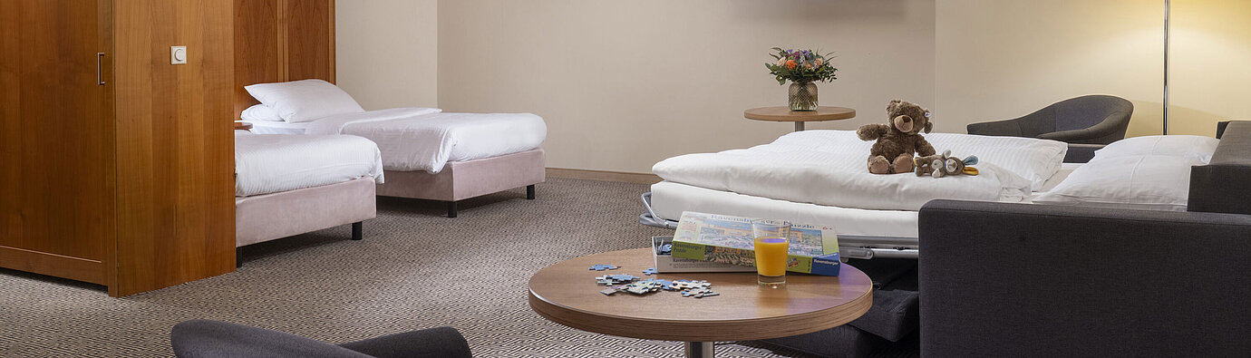 Large family room with TV, sofa bed, toys and puzzle at the Maritim Hotel Stuttgart