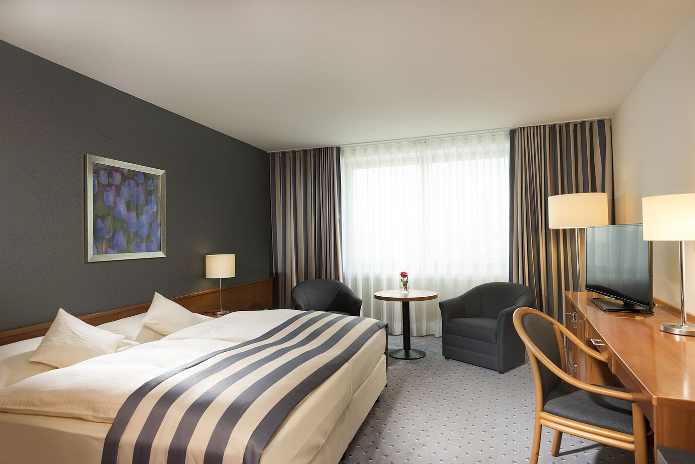 Chambre double spacieuse au Maritim Hotel Ulm avec lumière naturelle et coin salon