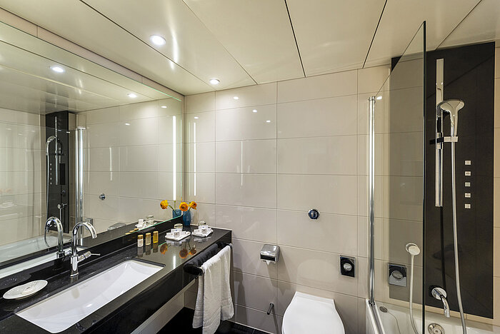 Salle de bain moderne avec baignoire, grand miroir, robinetterie élégante et équipements haut de gamme au Maritim Hotel Ulm.