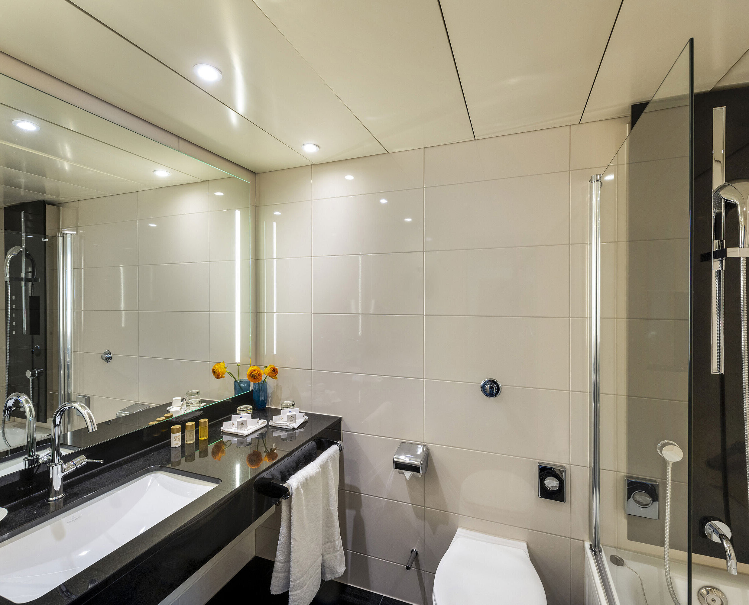 Salle de bain moderne avec baignoire, grand miroir, robinetterie élégante et équipements haut de gamme au Maritim Hotel Ulm.