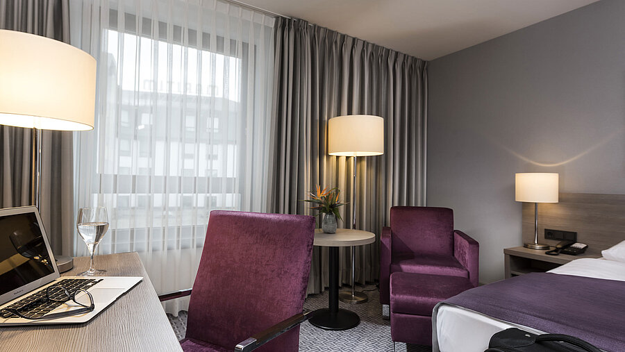 Habitación individual elegante del Maritim Hotel Königswinter con escritorio, sillón y diseño moderno.