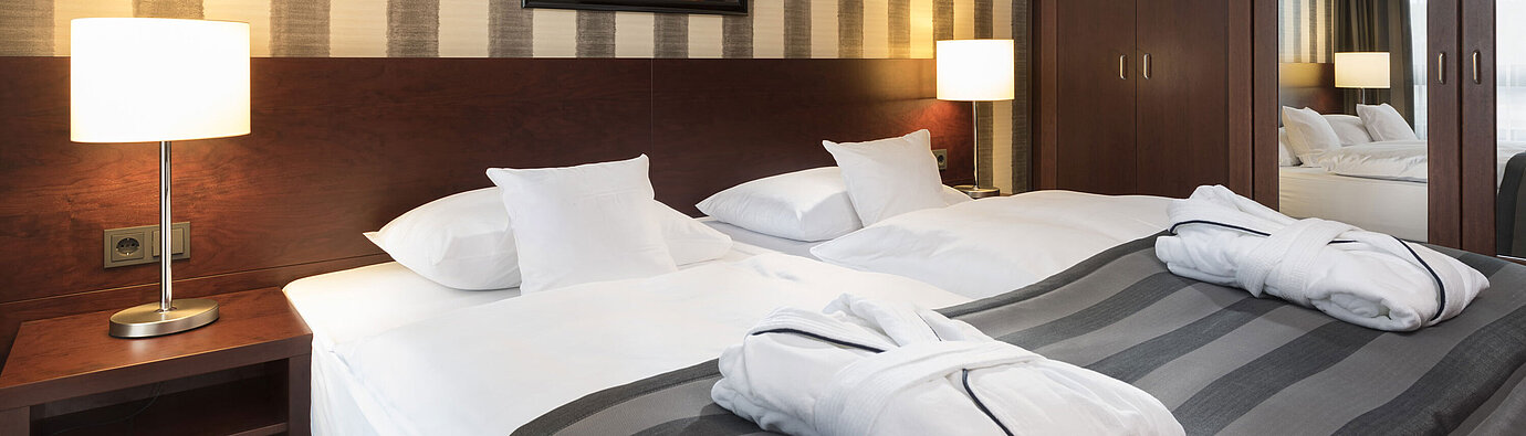 Suite Junior Camera doppia moderna con letto accogliente, accappatoi e interni eleganti al Maritim Hotel Königswinter.