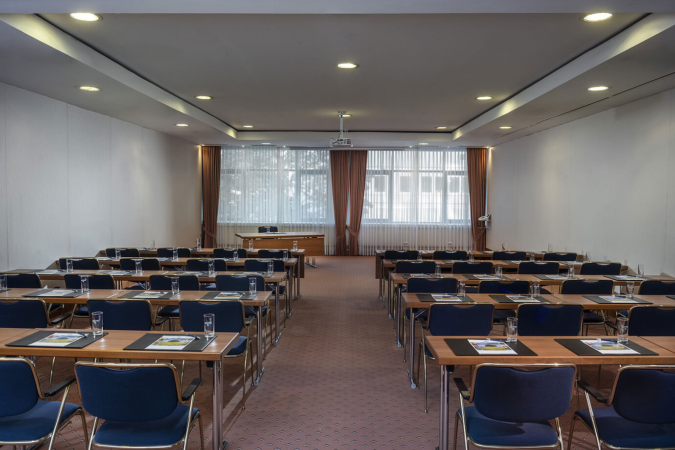 Salle de réunion moderne au Maritim Hotel Magdeburg avec sièges en rangée, lumière naturelle et équipement technique.