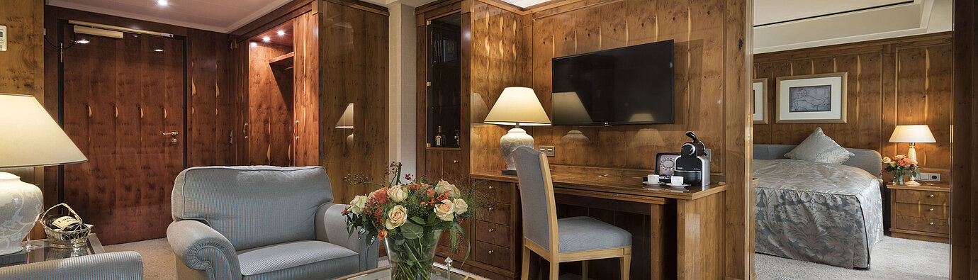Penthouse suite with living room, wooden furniture, desk, and view into bedroom at Maritim Seehotel Timmendorfer Strand.