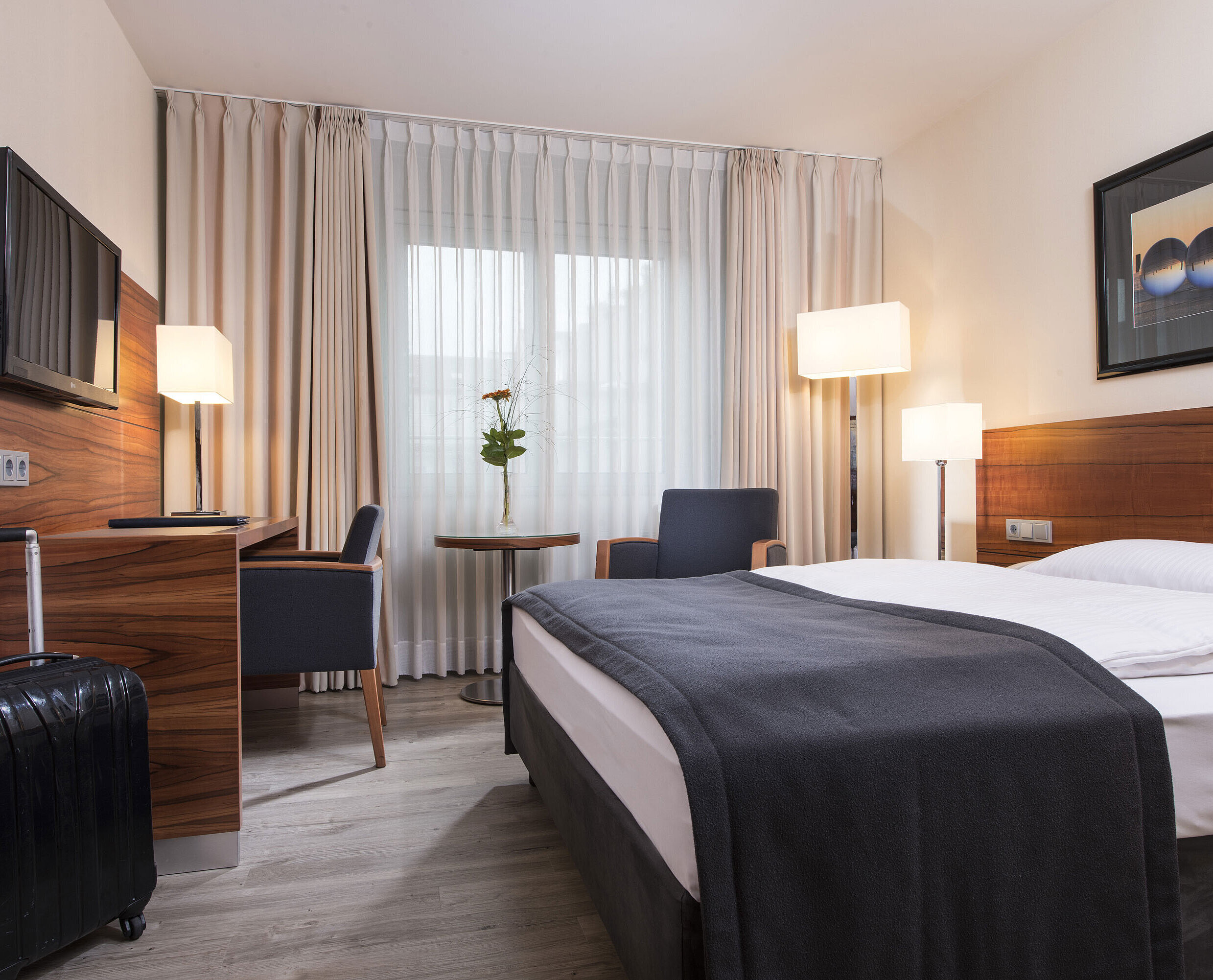 Hotel room for allergy sufferer Cosy room with double bed, desk and suitcase at the Maritim Hotel Munich