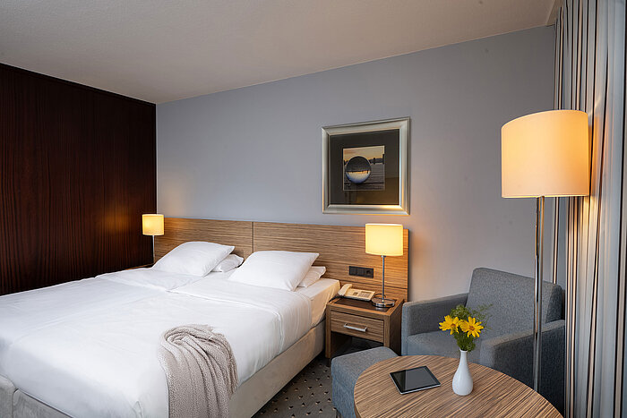Accogliente area salotto e comodo letto nella camera Comfort del Maritim Hotel Darmstadt