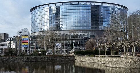 Exterior view of Maritim Hotel Frankfurt with modern glass facade and adjacent pond in daylight.