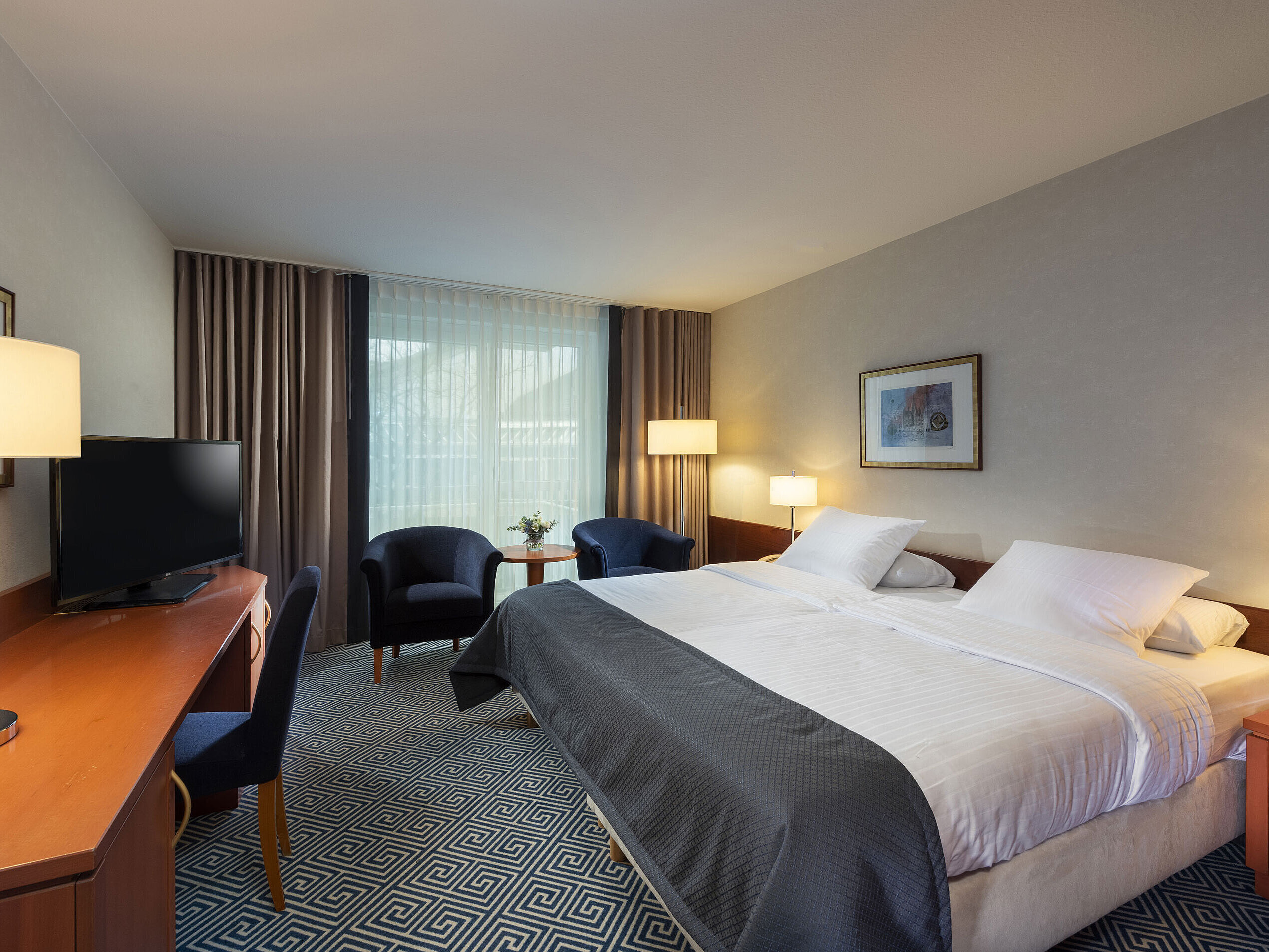 Habitación doble de estilo atemporal en el Maritim Hotel Würzburg con cama grande y ambiente acogedor