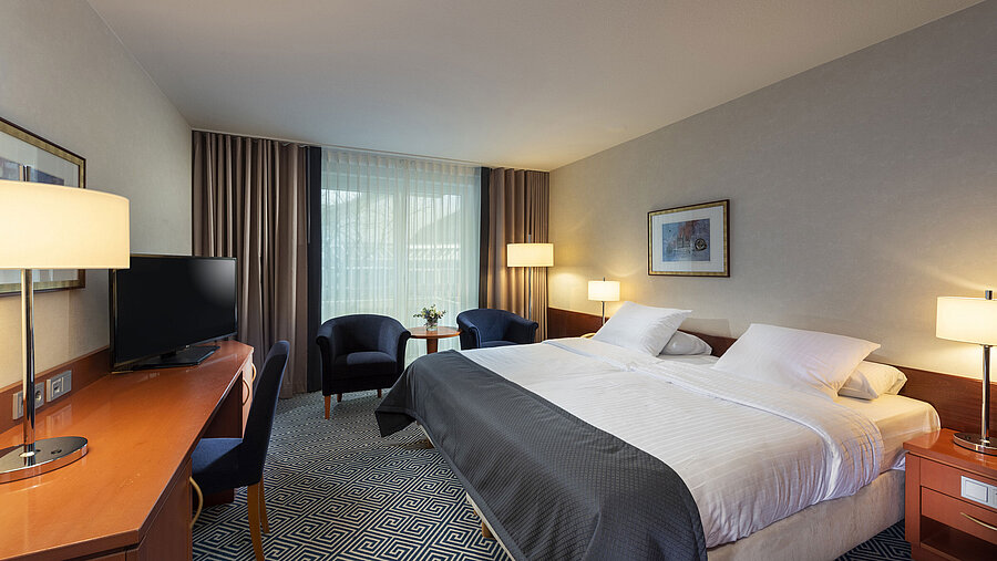 Habitación doble de estilo atemporal en el Maritim Hotel Würzburg con cama grande y ambiente acogedor